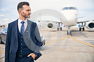 Young businessman posing in front of a plane