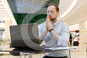Young businessman practicing breathing exhalation exercises working online to manage stress and calm down
