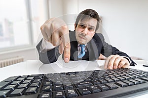Young businessman is pressing enter key on keyboard and submitting a form