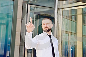 A young businessman pushes his index finger against a virtual sc