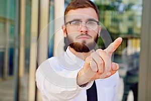 A young businessman pushes his index finger against a virtual sc