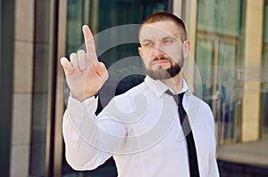 A young businessman pushes his index finger against a virtual screen