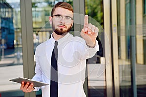 A young businessman pushes his index finger against a virtual screen