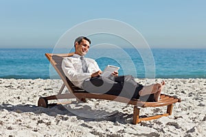 Young businessman relaxing on a deck chair using his tablet