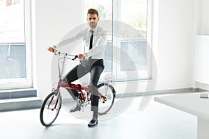 Young Businessman Rides on His Bike at Office. Business People