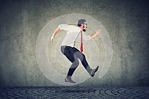 Young businessman running jumping against wall background