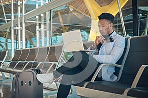 Young businessman is seated in the airport working with a laptop