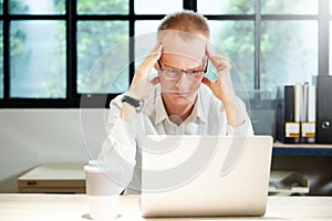 Young businessman seriously working on computer laptop in office