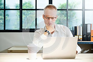 Young businessman seriously working on computer laptop in office