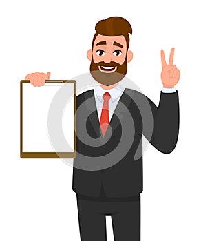 Young businessman showing blank clipboard and making victory, V, peace or two gesture hand sign. Person holding notepad.