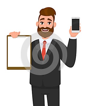Young businessman showing blank clipboard and new brand mobile or smartphone in hand. Person holding notepad. Male character.