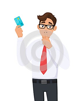 Young businessman showing credit, debit, ATM card and asking silence please. Keep quiet. Shut up. Person holding digital payment.