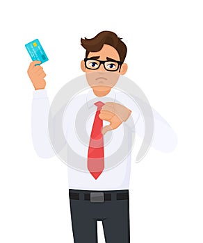 Young businessman showing credit, debit, ATM card and making thumb down gesture sign. Person holding digital payment card.