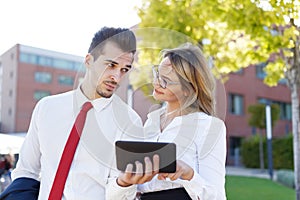 Young businessman showing digital tablet to businesswoman outdoors