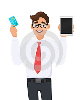 Young businessman showing new tablet computer and credit, debit or ATM card in hand. Person holding digital tab. Male character.