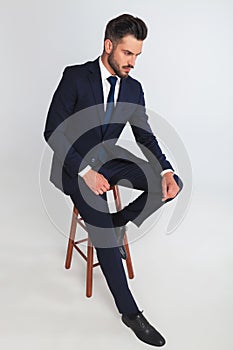 Young businessman sits on chair and looks down to side