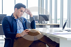 A young businessman sitting in a modern office. He has a feel stressed about the result of business profits not positive. On his