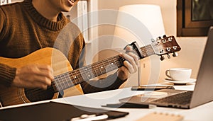 Young businessman sitting and playing guitar in office