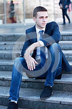 Young businessman sitting on the steps of the office