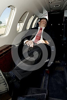 Young businessman sleeping in corporate jet