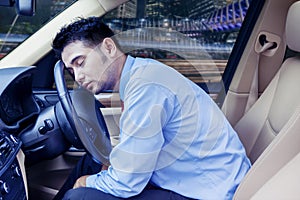 Young businessman sleeping inside his car