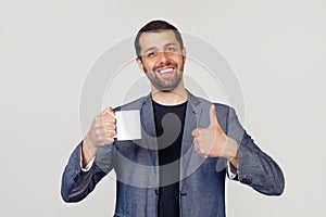 Young businessman with a smile, a man with a beard in a jacket, holding a cup of coffee and showing a thumb up gesture, a man with