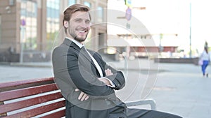 Young Businessman Smiling at Camera while Sitting on Bench