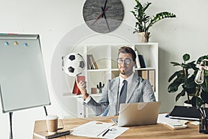 young businessman spinning soccer ball on finger