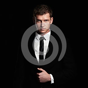 Young Businessman standing on black background. handsome Man in suit and tie