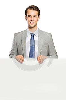 Young businessman standing with a blank whiteboard , isolated