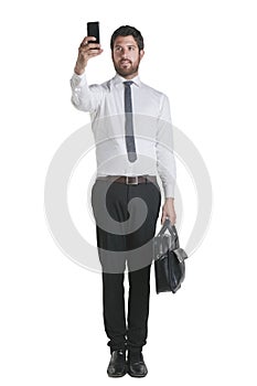 Young businessman standing with briefcase and working with smartphone.