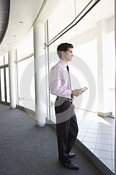 Young Businessman Standing In Corridor Of Modern Office Building