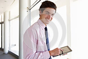 Young Businessman Standing In Corridor Of Modern Office Building