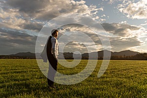 Young businessman standing in green meadow gazing into the distance