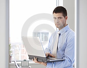 Young businessman standing with laptop in hand