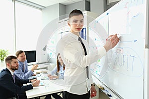 Young businessman stands near board with graphs and demonstrates statistics