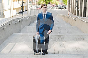 young businessman in stylish suit with luggage
