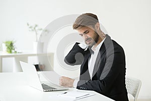 Young businessman in suit feeling neck pain after sedentary work photo