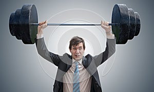 Young businessman in suit is lifting heavy weights