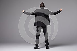 Young businessman in suit raised hands back side