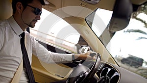 Young businessman in sunglasses driving cool car, elite transportation service