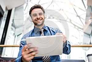 A young businessman with tablet and headphones in a modern building.