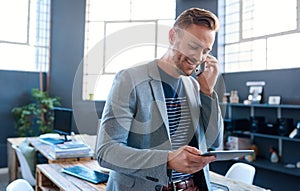 Young businessman talking on his cellphone and using a tablet