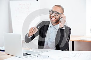 Young businessman talking on mobile phone and looking at camera