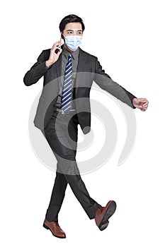 Young businessman talking on  mobile phone, walking and wearing a protective medical mask isolated on white background