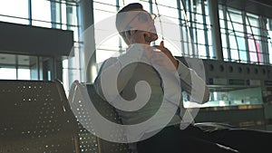 Young businessman talking on phone at airport with sun flare at background. Portrait of handsome business man in