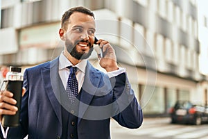 Young businessman talking on the smartphone and holding bottle of water at the city