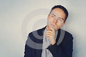 A young businessman in a thoughtful pose reflects on business. Thinking through ideas and plans. A grown guy on a blue background