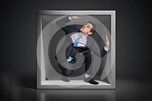 Young businessman trapped inside uncomfortable small box photo