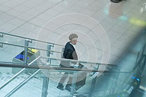 Young businessman traveling going down a stairway smiling up